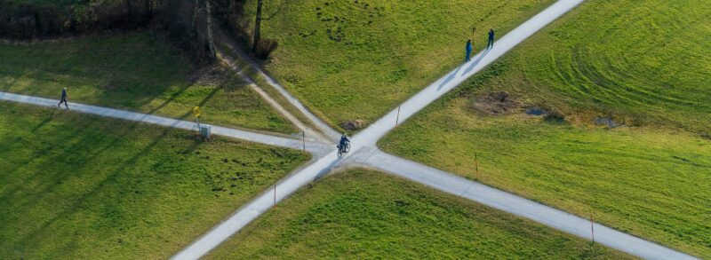 Aerial view of intersecting pathways across green fields, symbolising a mid-year pause, reflection and choosing the way forward.